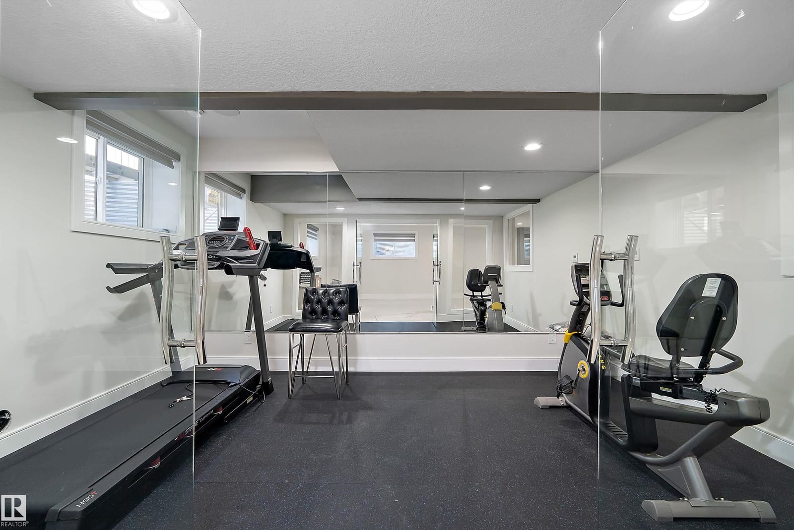 Home gym with rubber flooring and mirrored wall